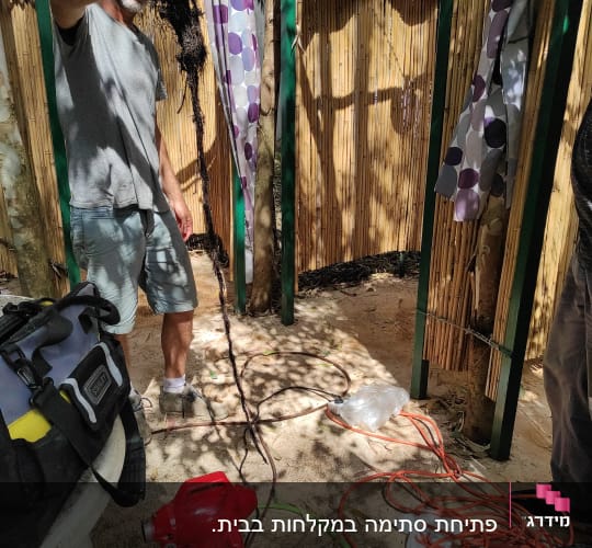 אדם מחזיק שורש סתום, כלי עבודה וצינור על הרצפה